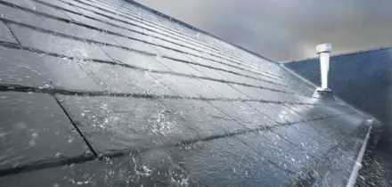 Regen op een donker leien dak met een metalen schoorsteen